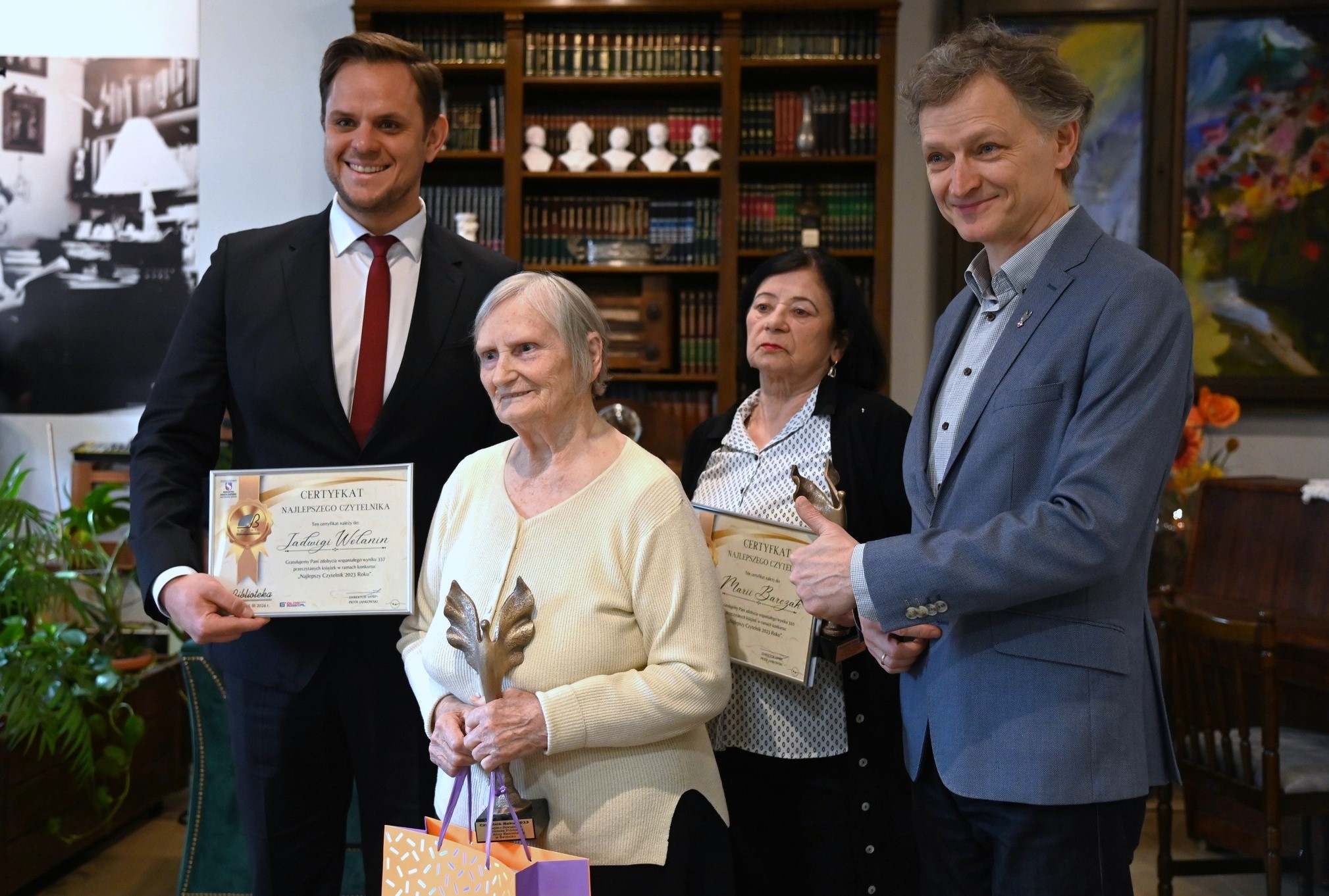 nagrodzone dwie kobiety ze statuetkami w ręku obok dyrektora biblioteki i zastepcy burmistrza