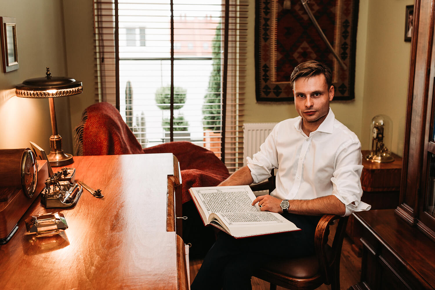 pisarz Max Czornyj siedziący z książką przy eleganckim biurku