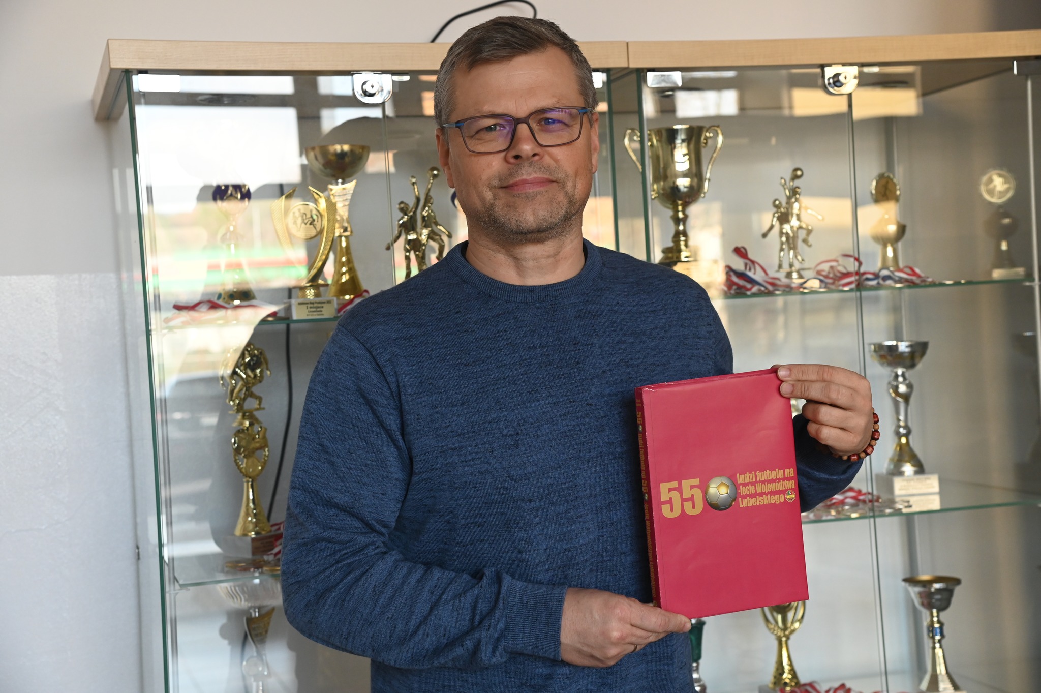 Jacek Kosierb Jacek Kosierb prezentujący swoją książkę na tle szklanej biblioteczki z pucharami